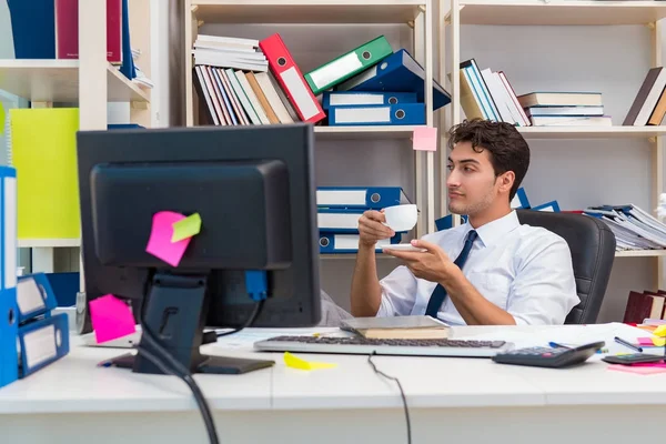 Zakenman werkzaam in het kantoor met stapels boeken en papieren — Stockfoto