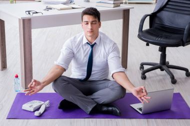 Adam stresle baş etmek için ofiste meditasyon yapıyor.