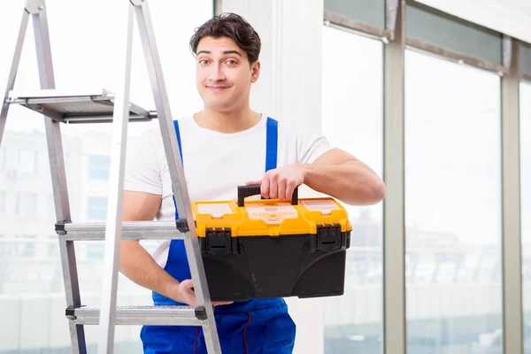 Jovem reparador subindo escada no local de construção — Fotografia de Stock
