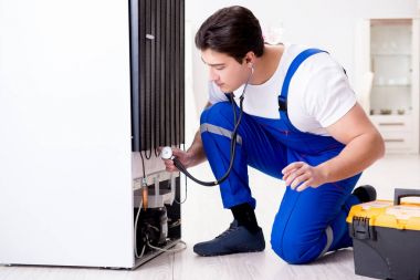 Tamirci müteahhit DIY konseptinde buzdolabını tamir ediyor.