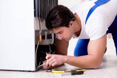 Tamirci müteahhit DIY konseptinde buzdolabını tamir ediyor.