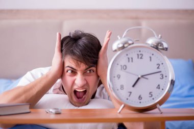 Yataktaki adam alarm yüzünden uykusuzluk çekiyor.