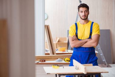 Genç bir marangoz dairesel testereyle odun kesiyor.