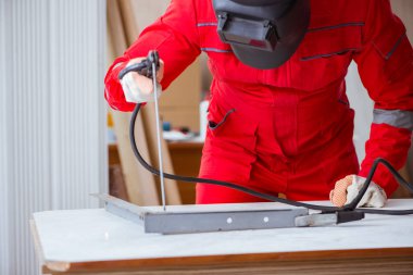 Kaynak tabancası elektrot ve kask takan genç bir tamirci.