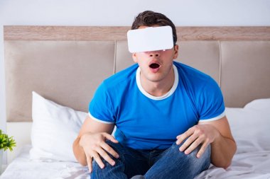 Yatakta sanal gerçeklik başlığı takan genç bir adam.