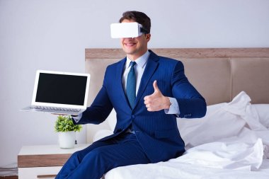 Yatak odasında sanal gerçeklik kulaklığı takan bir iş adamı.