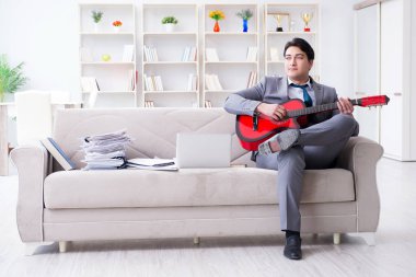 Evde gitar çalan bir iş adamı.