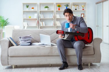 Evde gitar çalan bir iş adamı.