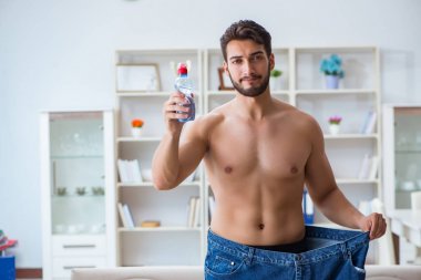 Kilo verme konseptinde büyük beden pantolon giyen bir adam.