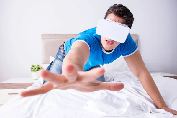 Молодой человек в постели в комплекте виртуальной реальности — стоковое фото