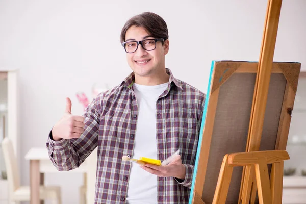 Genç erkek sanatçı parlak stüdyoda resimler çiziyor. — Stok fotoğraf
