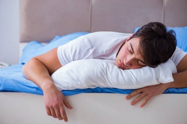 Uykusuzluk çeken bir adam yatakta yatıyor.