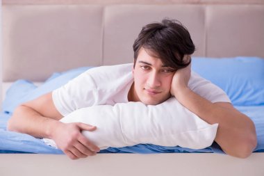 Uykusuzluk çeken bir adam yatakta yatıyor.