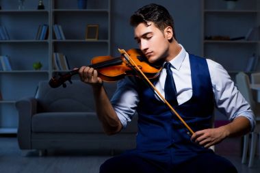 Genç müzisyen evde keman çalıyor.