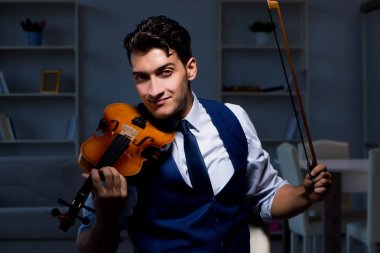 Genç müzisyen evde keman çalıyor.