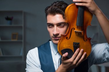 Genç müzisyen evde keman çalıyor.