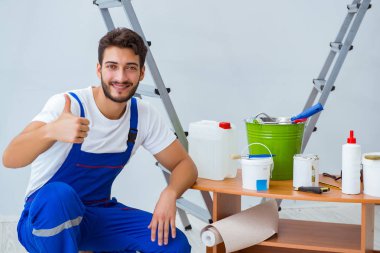 Tamirci, duvar kağıdıyla evde tadilat yapıyor.