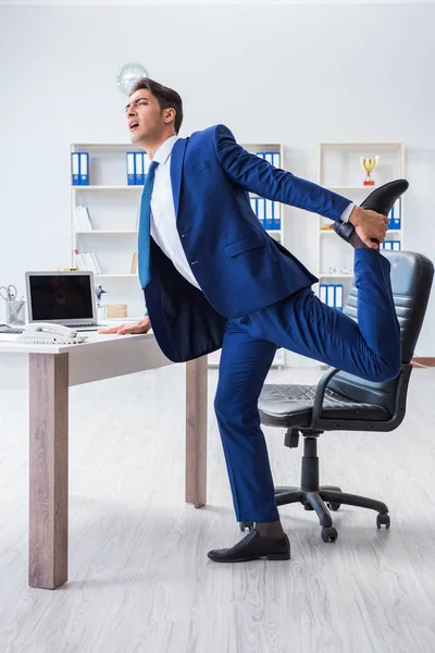 Joven empresario haciendo deporte estiramiento en el lugar de trabajo —  Fotos de Stock