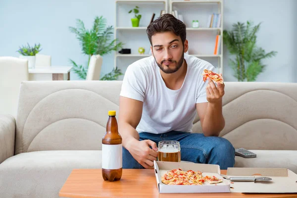 Man eating pizza having a takeaway at home relaxing resting