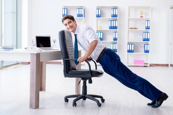 Young businessman doing sports stretching at workplace — Stock Photo, Image