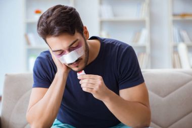 Genç adam estetik cerrahi burnundan sonra evde iyileşiyor.