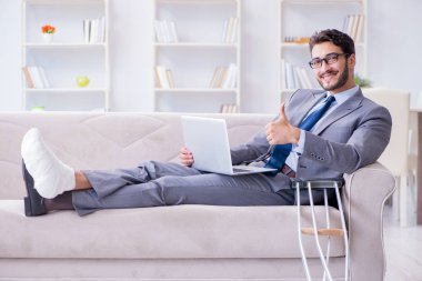 Koltuk değneği ve kırık bacağı olan bir iş adamı.