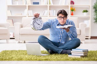 Genç yakışıklı adam evde yerde oturuyor.