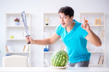 Evde karpuz yiyen bir adam.