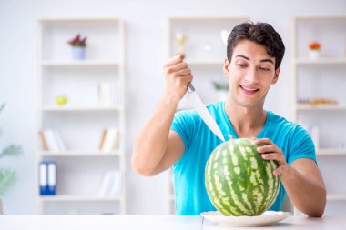 Evde karpuz yiyen bir adam.