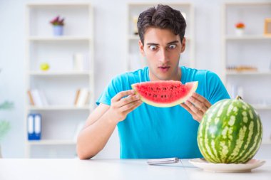Evde karpuz yiyen bir adam.