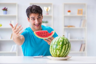 Evde karpuz yiyen bir adam.