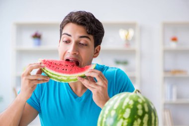 Evde karpuz yiyen bir adam.