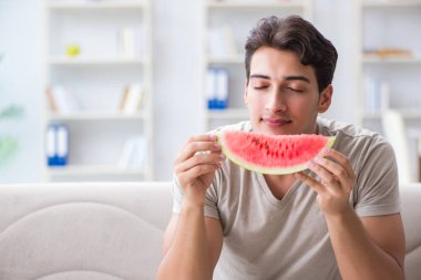 Evde karpuz yiyen bir adam.
