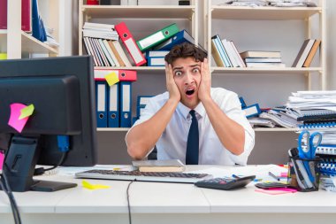 Ofiste kitap ve kağıtlarla çalışan bir işadamı.