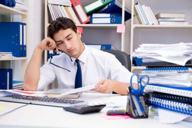 Ofiste kitap ve kağıtlarla çalışan bir işadamı.