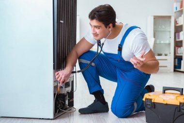 Tamirci müteahhit DIY konseptinde buzdolabını tamir ediyor.