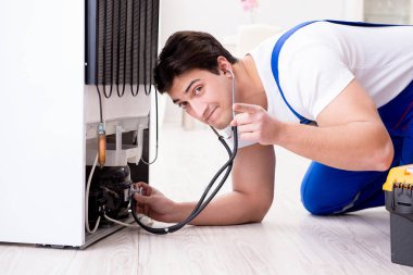 Tamirci müteahhit DIY konseptinde buzdolabını tamir ediyor.
