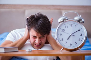Yataktaki adam alarm yüzünden uykusuzluk çekiyor.