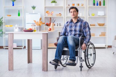 Engelli genç koca mutfakta çalışıyor.