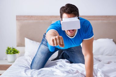 Yatakta sanal gerçeklik başlığı takan genç bir adam.