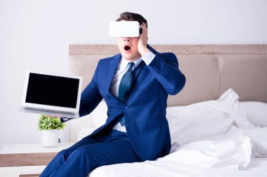 Yatak odasında sanal gerçeklik kulaklığı takan bir iş adamı.