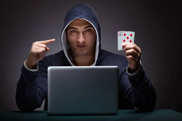 Jovem usando um capuz sentado na frente de um computador portátil — Fotografia de Stock