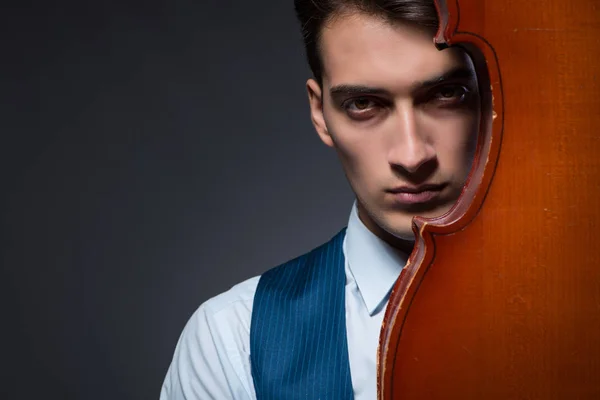 Young man playing cello in dark room — Stock Photo, Image