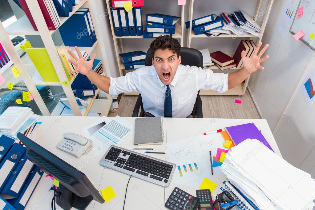 Businessman working in the office with piles of books and papers