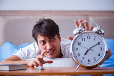 Yataktaki adam alarm yüzünden uykusuzluk çekiyor.