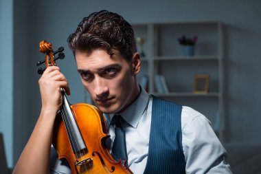 Genç müzisyen evde keman çalıyor.