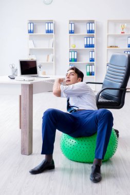 Genç işadamı iş yerinde spor yapıyor.