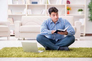 Genç yakışıklı adam evde yerde oturuyor.