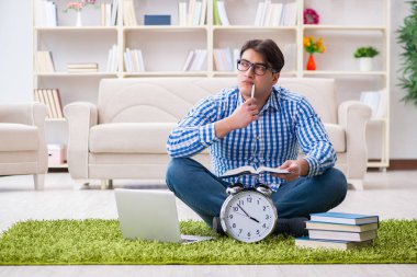 Genç yakışıklı adam evde yerde oturuyor.