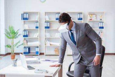 Ofiste egzersiz yapan işadamı VR gözlüğü takıyor.